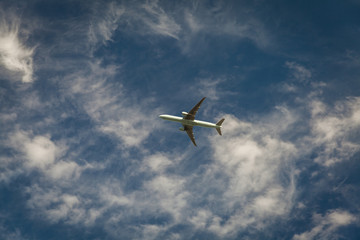 A plane flying blue sky with clouds in the background