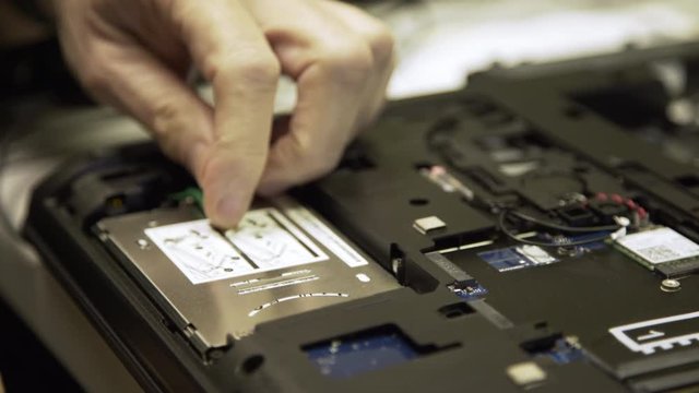 computer tech removing a hard drive from a laptop