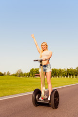 Pretty happy girl with raised hand riding a segway
