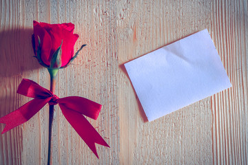red rose put on white blank paper on wooden background, valentine concept.