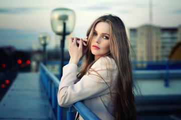 Beautiful lonely young pretty girl standing on the city roof in the sunset. Sensual evening...