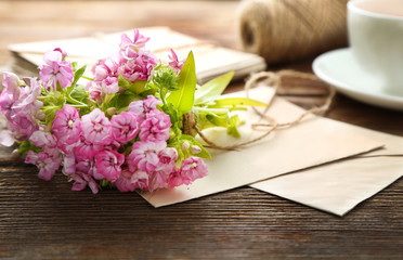 Bouquet of meadow flowers, envelope on wooden table