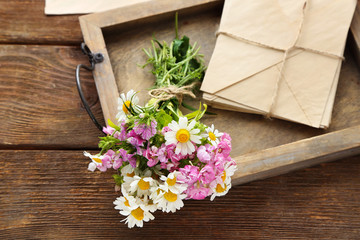 Bouquet of meadow flowers with envelopes on wooden table