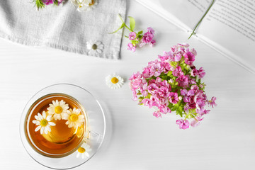 Beautiful meadow bouquet and tea on light background