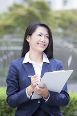 Fototapeta premium バインダーを持つ若い女性 屋外ビジネスイメージ