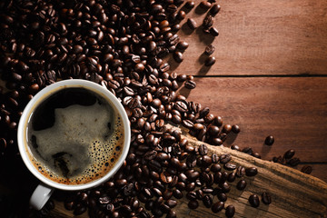 Top view of Coffee cup and coffee beans on a wood background with copy space.