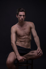 Obraz na płótnie Canvas Nude young man model posing sitting Caucasian skinny, slim, fit