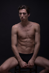 Fototapeta premium Nude young man posing model sitting Caucasian skinny, slim, fit