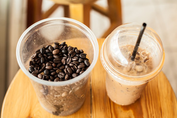 cup of ice coffee with coffee beans on wooden chair