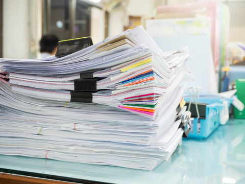 Pile of unfinished paperwork on office desk