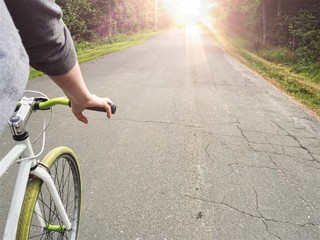 Teen riding bike by the sun road.