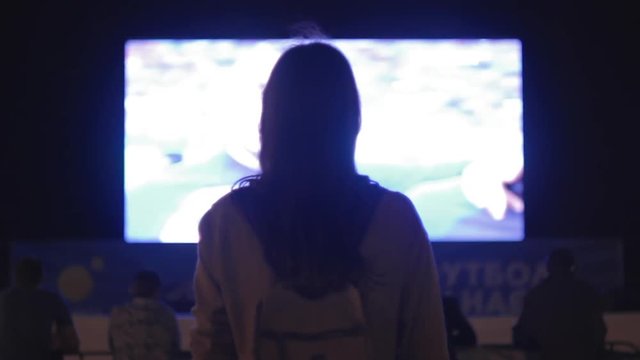  Beautiful girl looking video on the big screen at night