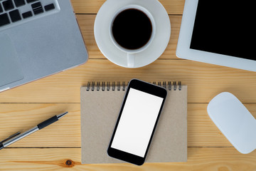 Office stuff with blank screen smartphone, laptop, tablet, mouse, pen, leather notebook and cup of coffee. Top view gadgets.