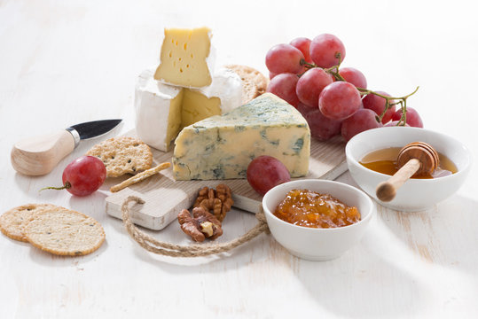 molded cheeses, fruit and snacks on a white wooden table