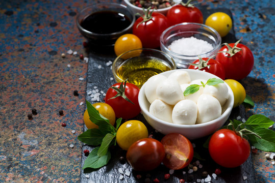 mozzarella, fresh vegetables and spices on a dark background