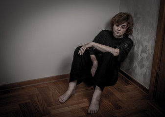 Fototapeta na wymiar Depressed and sad woman sitting on the floor in the empty room. Low key.
