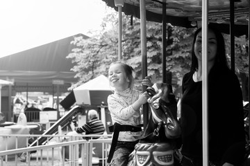 Mom and daughter in the park and ride on the carousel