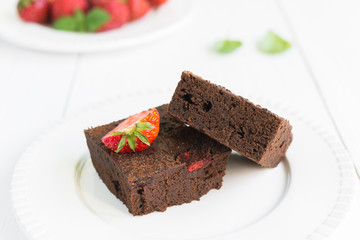 Chocolate brownie cake on white plate decorated with strawberrie