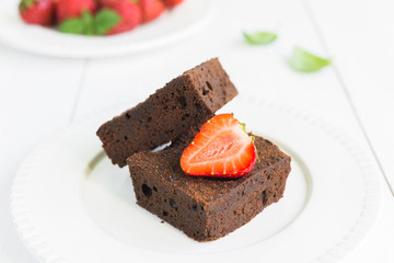 Chocolate brownie cake on white plate decorated with strawberrie