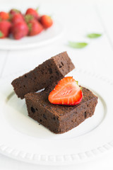 Chocolate brownie cake on white plate decorated with strawberrie