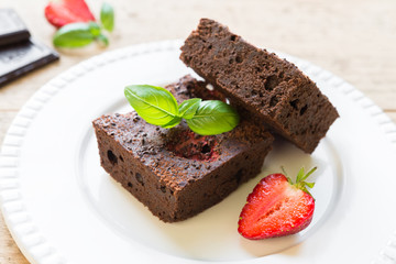 Fototapeta na wymiar Chocolate brownie cake on white plate decorated with strawberrie