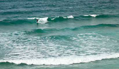 Atlantic ocean waves at the beach Amado. Silhouette of a surfer on the crest of a wave. Sagres, Algarve, Portugal