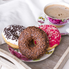 donuts and cup of coffee on wood background