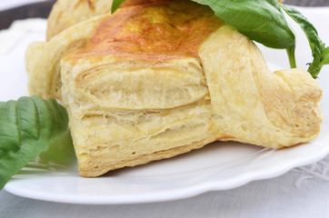 Close_up puff pastry pies with egg and cheese a plate on wooden background ,green spice.