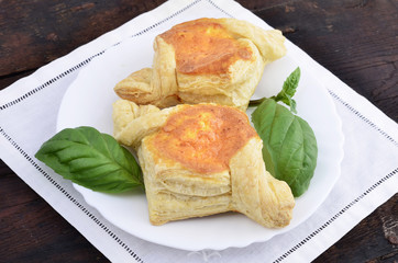 Puff pastry pies with egg and cheese a plate on wooden background ,green spice