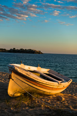 Boat on a beach at sunset with ruins of old roman fortress in backround, Sithonia, Greece