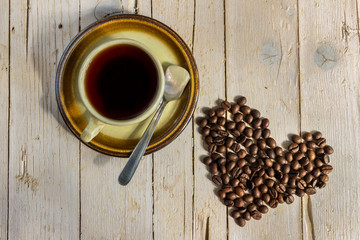 Чашка черного кофе и кофейные зерна на деревянном фоне.