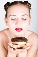 girl in bright makeup eating a tasty donut with icing. Funny joyful woman with sweets, dessert. dieting concept. junk food. girl with tenderness looks at a donut