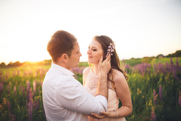 Beautiful couple, bride, groom kissing and hugging in the field sunset