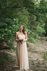 Fototapeta na wymiar Beautiful luxury young bride inwedding dress standing near river with mountains on background