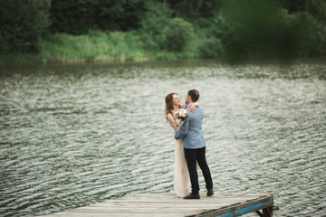 Elegant beautiful wedding couple posing near a lake at sunset