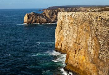 Seascape with cliffs of Cape St. Vicente and the unknown fisherman over a sea gulf, Sagres, Cabo de S. Vicente, Algarve, Portugal