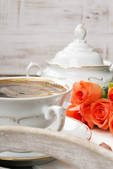cup of coffee and a bouquet of roses on a tray