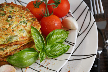 Vegetarian zucchini fritters served with fresh herbs, tomatoes a