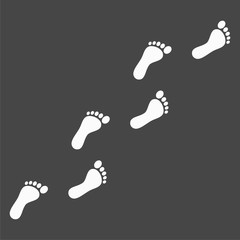 Trail of human bare footsteps on black background