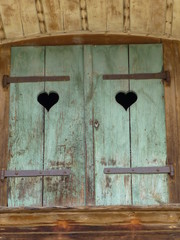 Pair of faded green shutters on traditional wooden building in Swiss village