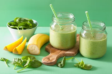Photo sur Plexiglas Milk-shake healthy green smoothie with spinach mango banana in glass jars