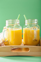 healthy yellow smoothie with mango pineapple banana in mason jar