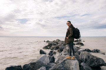 Backpacker standing on rocks on shore