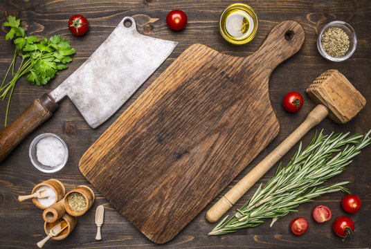 old cutting board with spices and herbs for cooking meat with cherry tomatoes and meat ax place for text,frame