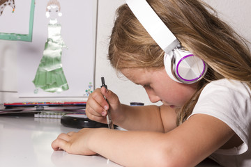 Naklejka premium Kind hört Musik mit Kopfhörern und malt mit Zirkel