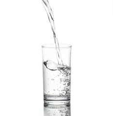 Fotobehang Water poured in a glass transparent white backdrop. © PhotoJuthamat