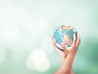 Earth day concept: Earth globe in human hands over blurred nature background. Elements of this...