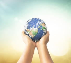 Earth day concept: Earth globe in human hands over blurred nature background. Elements of this image furnished by NASA