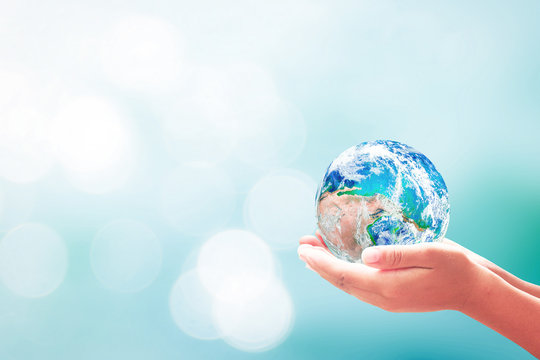 Earth Day concept: Earth globe in human hands over blurred nature background. Elements of this image furnished by NASA