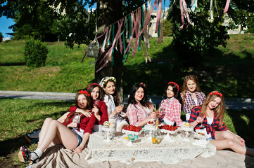 Fototapeta premium Seven happy and sexy girls sitting at picnic table on bacheloret